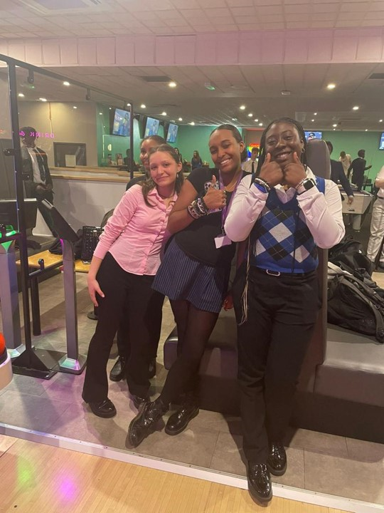 three sixth form students giving thumbs up at a bowling alley trip